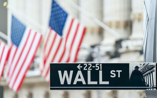 Slika znaka za Wall street v New Yorku ki kaze na financno ekonomsko in poslovno okrozje z ameriskimi zastavami na drogu v ozadju 07032023