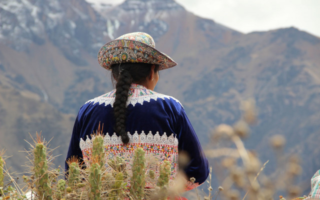 Slika prebivalke Andov v nosi v ospredju kaktusi v zamegljenem ozadju del Andov 10.12.2023