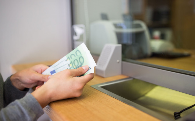 Slika zenskih rok blagajnicarke na banki ob stetju 100 evrskih bankovcev na bancnem okencu 13.2.2023