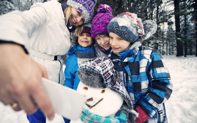 Mama in trije otroci delajo selfija s snežakom